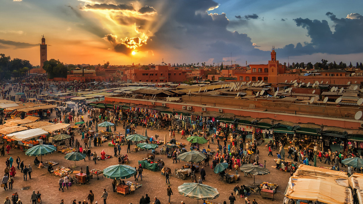 Vibrant scene of Jamaa Lafna Square in Marrakech, Morocco, bustling with people, market stalls, and street performers.