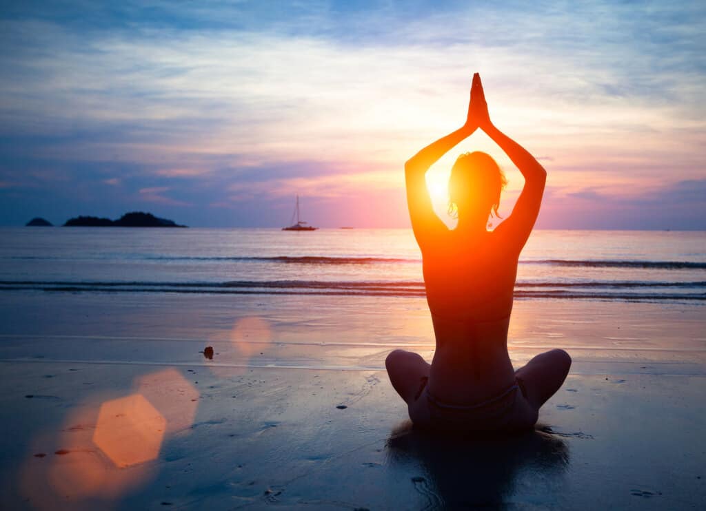 A girl practicing yoga on the beach, illustrating the topic of the blog post "Yoga on the Beach".