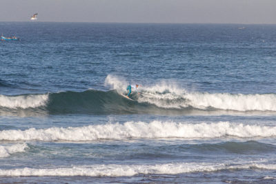 A surfer executing a beautiful maneuver at the QS surf competition in Anza, Morocco.