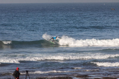 A surfer executing a beautiful maneuver at the QS surf competition in Anza, Morocco.