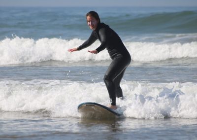 Una ragazza surfista impara a stare in piedi sulla sua tavola ad Agadir, un luogo ideale per i principianti nel surf in Marocco.