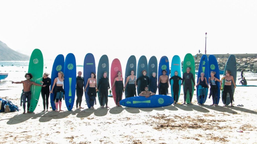 Gruppenfoto von Anfängersurfern, die Schaumstoff-Boards am Strand in Taghazout, Marokko, halten
