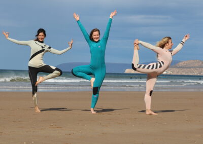 Guests of Azul Guesthouse who took the surf and yoga package, doing a yoga pose on the beach after warming up before the surf session.
