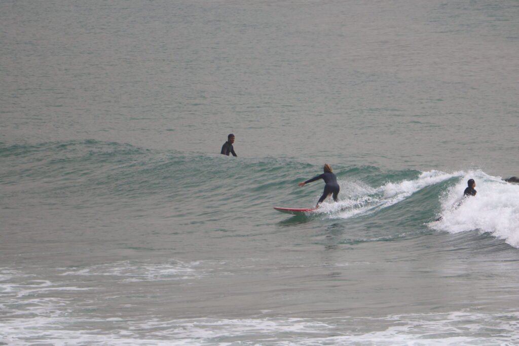 Surfeuse intermédiaire glissant sur une belle vague dans la baie d'Imsouane, Maroc, célèbre pour ses longues vagues parfaites.