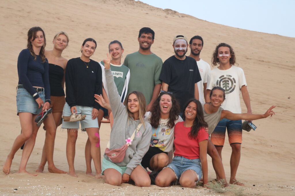 Groupe de surfeurs d'Azul Guesthouse glissant sur les dunes de Tamri au coucher de soleil après une journée de surf à Imsouane.