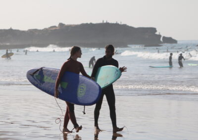 A beginner surfer receiving guidance from an instructor on the sandy shores of Crocro Beach, Morocco.