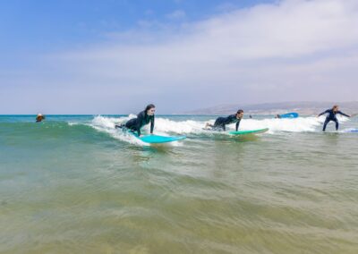 Dos surfistas principiantes montando una ola juntos en Taghazout, surf camp Marruecos