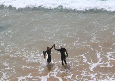 Dos surfistas se dan un high five tras una sesión guiada en Desert Point, Marruecos