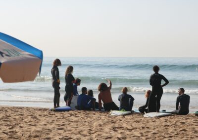 Coach de surf dando instrucciones de line-up en Banana Point, Marruecos, preparando a los surfistas para su próxima sesión.