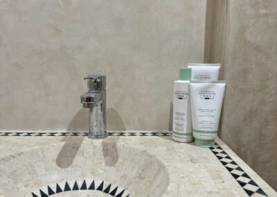 Lavabo moderne et miroir artistique dans la salle de bain de la chambre triple à Azul Guesthouse, Maroc.